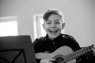 lachender junge mit gitarre auf dem gitarrenklassenkonzert auf schloss boitzenburg