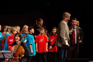 Moderator Attila Weidemann, Geschaeftsfuehrer des VdMK Winnetou Sosa und die Singklassenschueler*innen