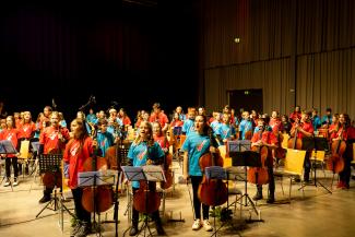Gruppe von Streicherinnen und Streichern erheben sich während des Streicherklassenkonzerts